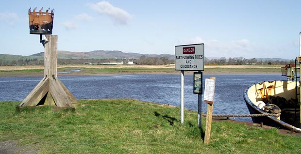 View from the quay at Glencaple across the River Nith with sign warning of fast flowing tides and quicksands